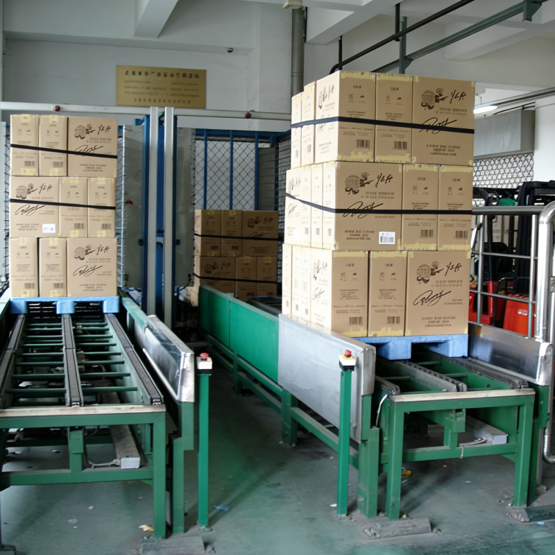 Automated conveyor line with pallets loaded with stacked cardboard boxes