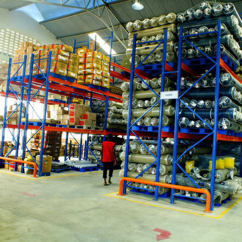 Warehouse racking with blue pallets holding fabric rolls and boxes