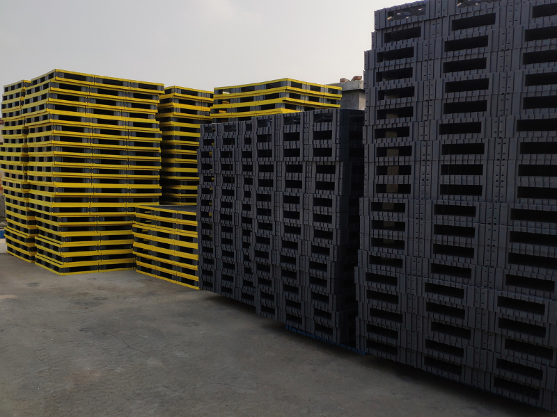 Factory stock of yellow and black modular plastic pallets
